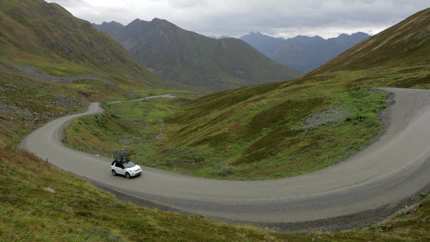 A car turns around a winding road in the mountains