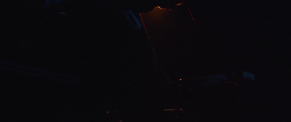 A red light shines overhead as a man rides a stationary bike