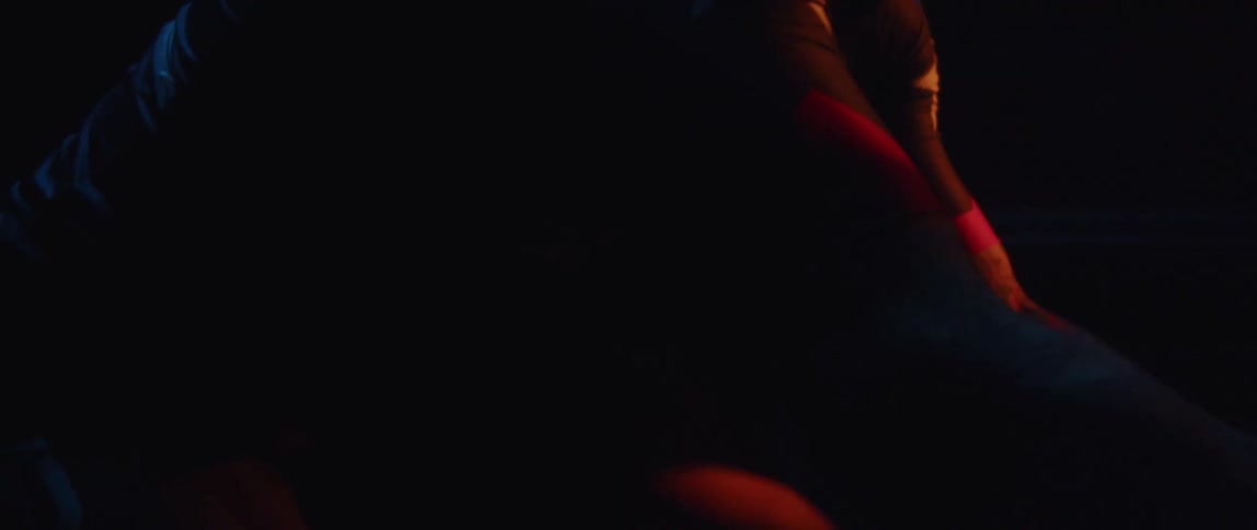 Man pedaling on a static bicycle inside a dimly lit room against a dark background