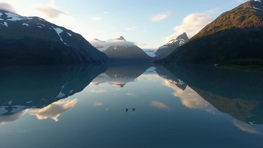 Two kayakers paddling on Portage lake in Alaska