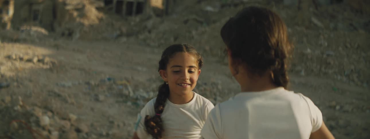 Two little girls laugh as they play and clap their hands together