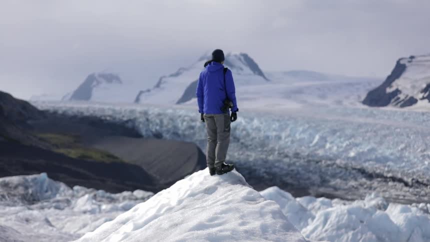 A man is standing over an icy mountain top