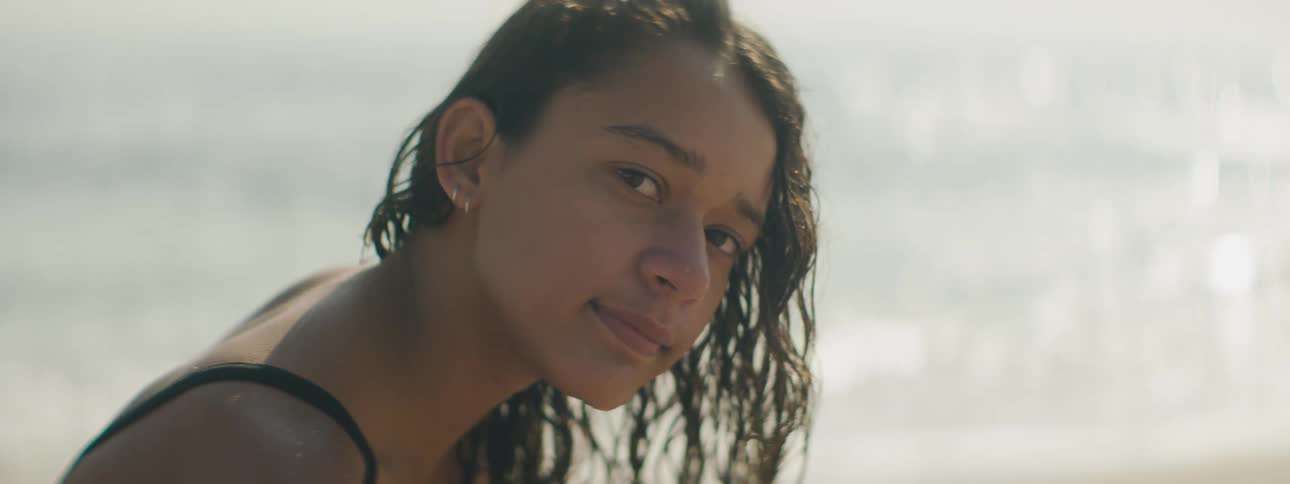 A woman is standing by the coast of the ocean