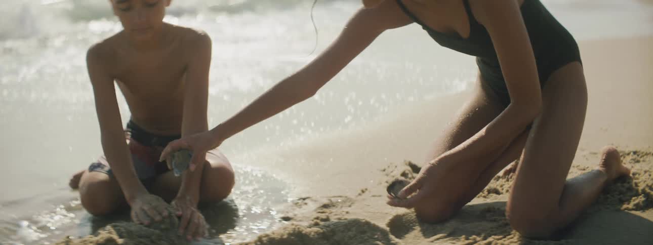A boy and a girl on the beach playing in the sand