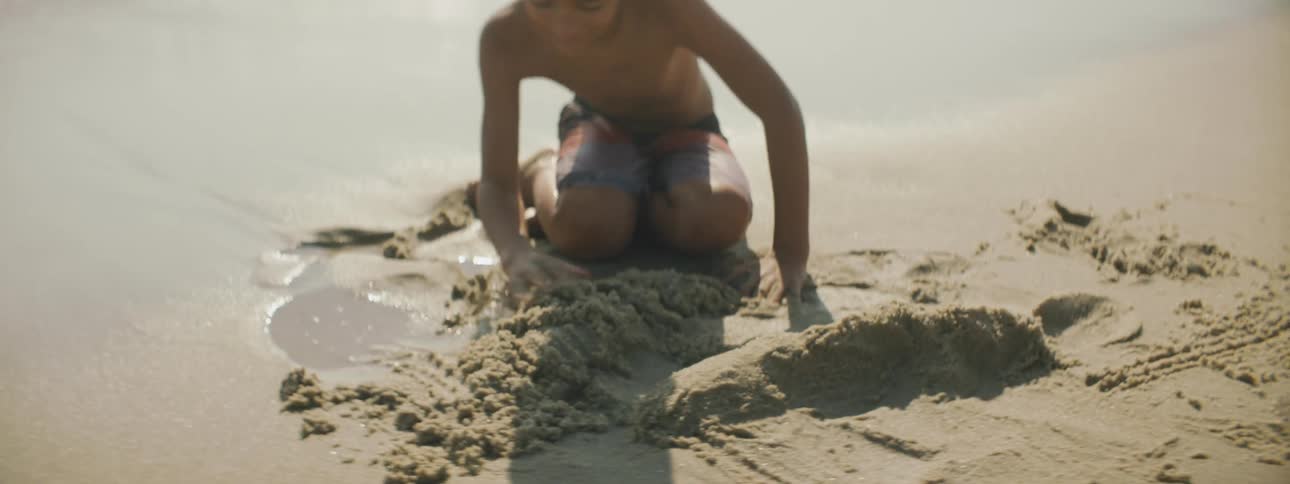 A brother and sister build sand castles on the beach