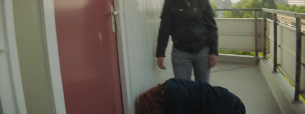 A boy and girl bully another boy on a building balcony kicking at him and pushing him down