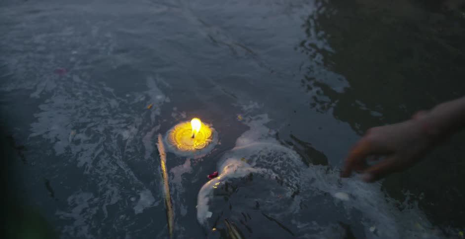 A woman setting a floating candle loose in a body of water