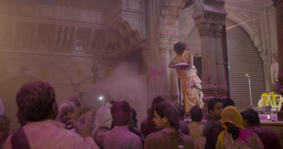 Woman throwing pink colored powder onto people in a crowd