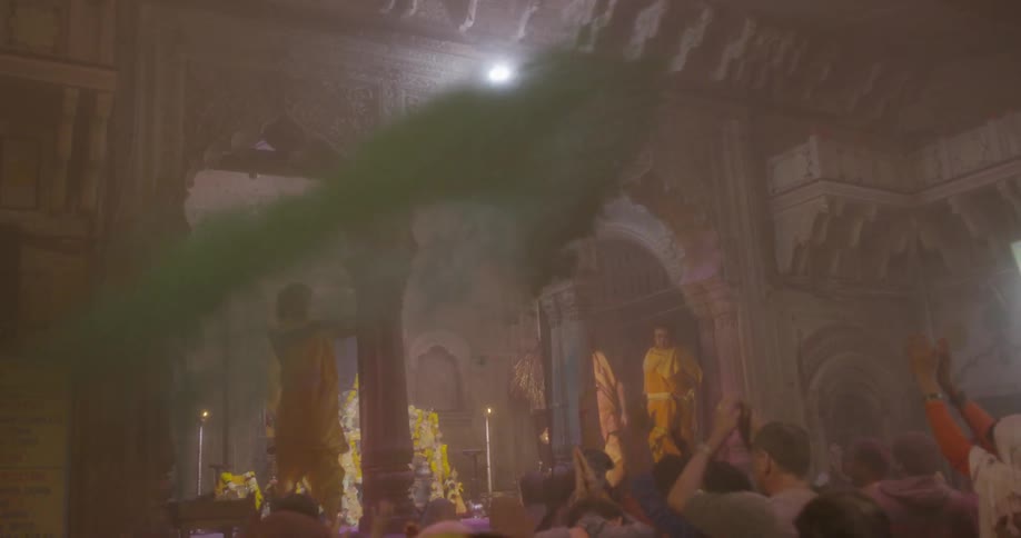 A man throws green powder on a jubilant audience