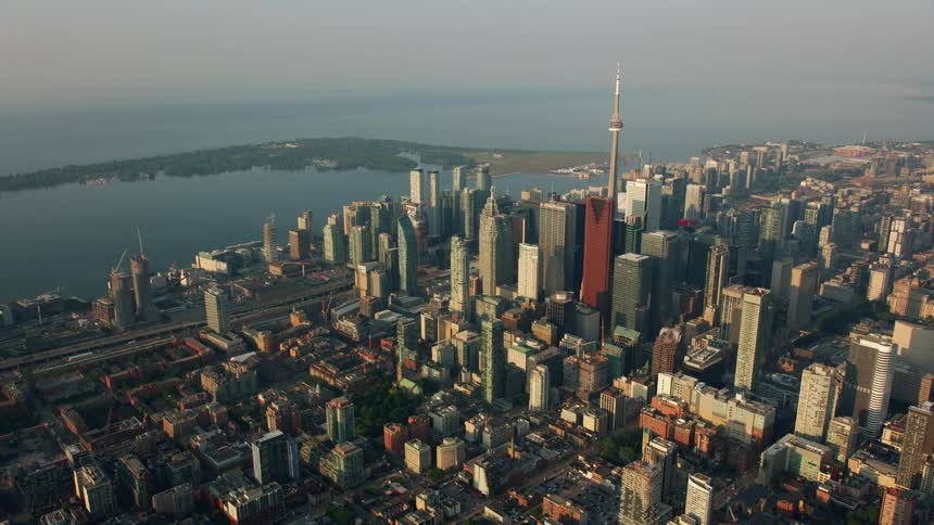 The cn tower stands tall above the toronto city skyscrapers on the lake ontario harbor