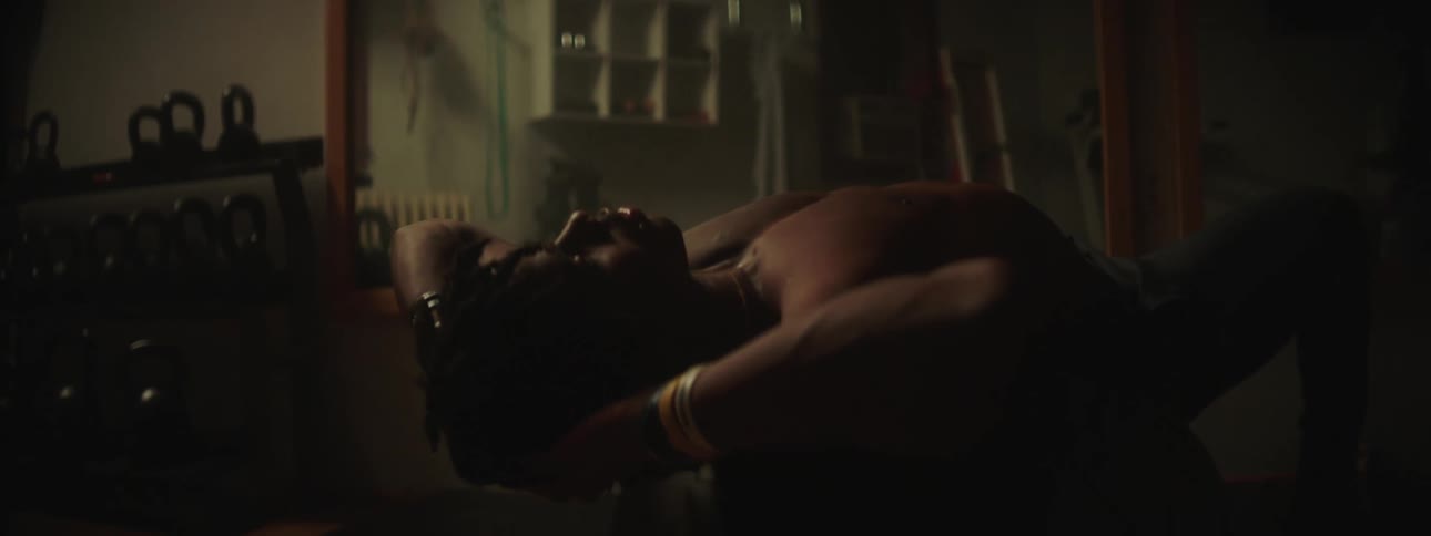 Man does crunches on an exercise ball in dim room