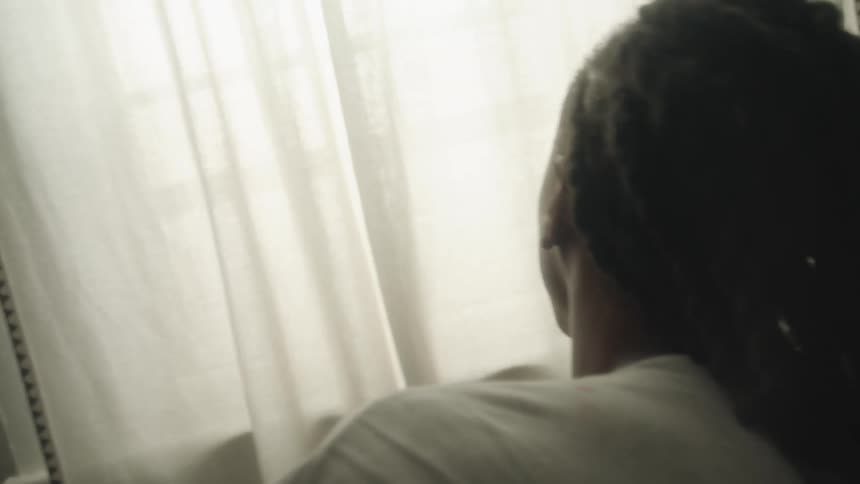 A young black man is laying down in his room