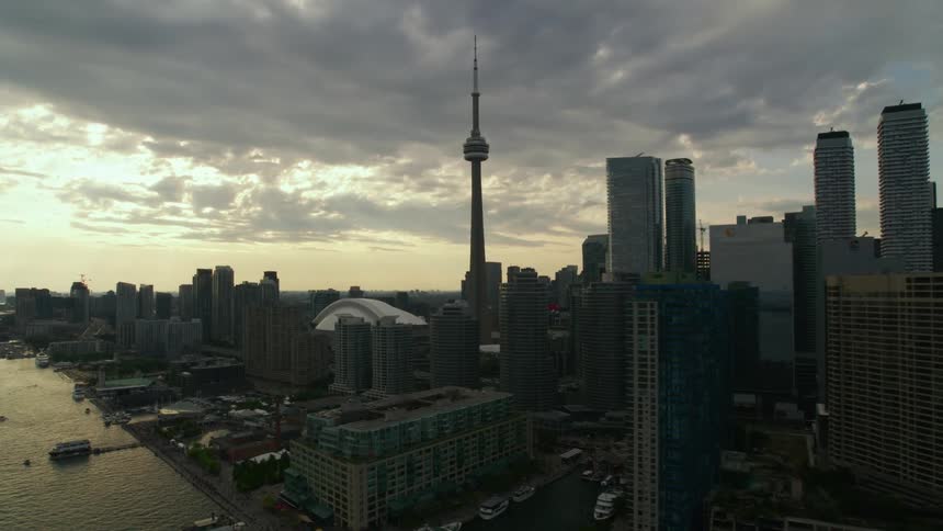 A tower and skyscrapers loom over a waterway in a metropolis on a cloudy day