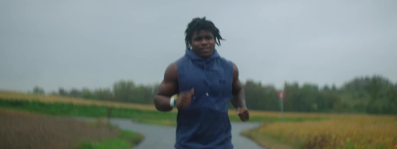 A man jogging on a narrow road in a rural area