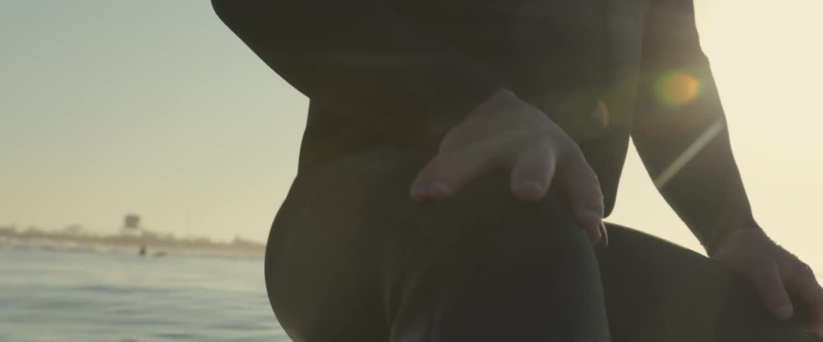 A person is surfing on ocean water during dusk