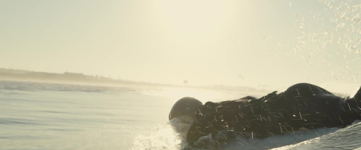 A man paddles on his surfboard in the ocean
