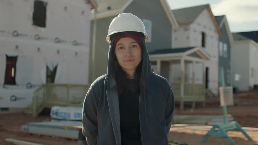 A woman stands on a construction site in a neighborhood
