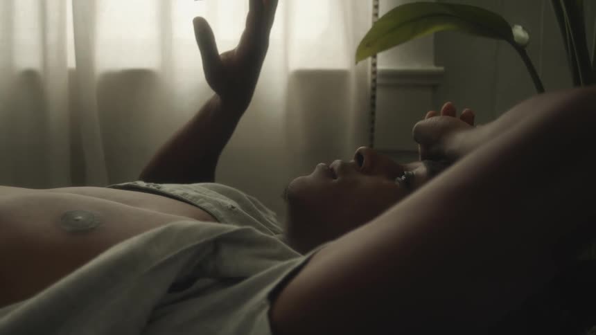 A man is laying down in his bedroom near a window