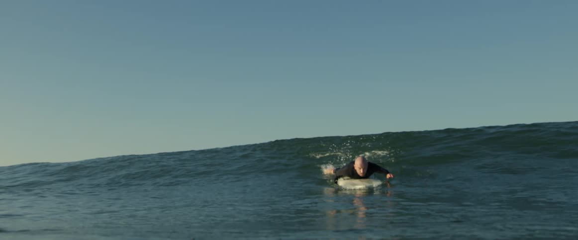 A man catches a wave and surfs toward shore