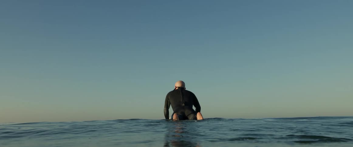 A man on a surfboard looking around enjoying the calm ocean