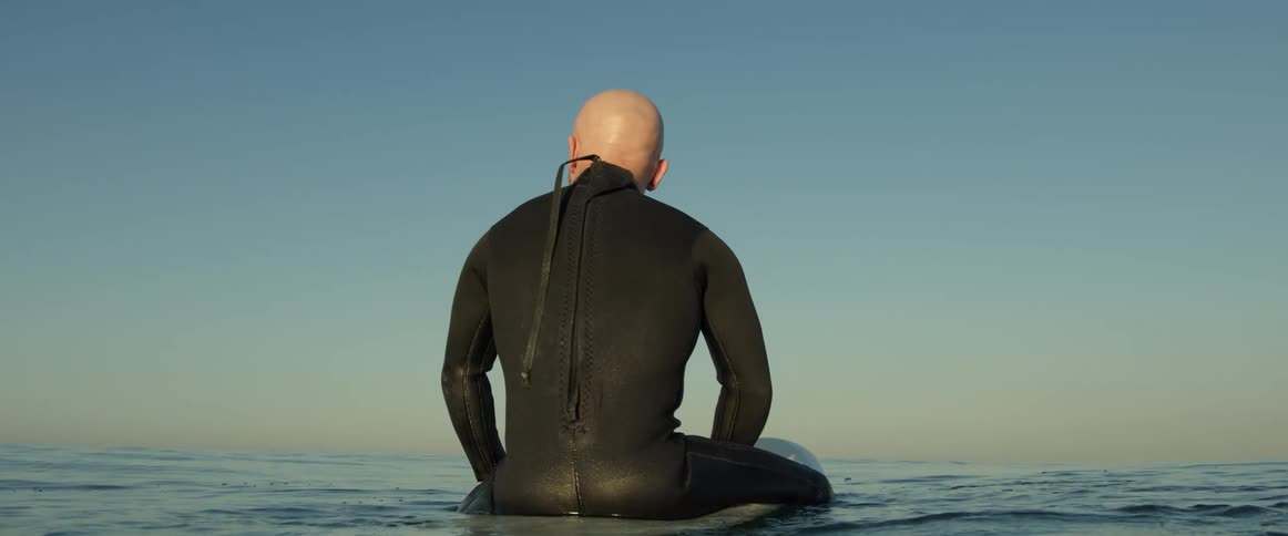 A man sits on a surf board in the ocean