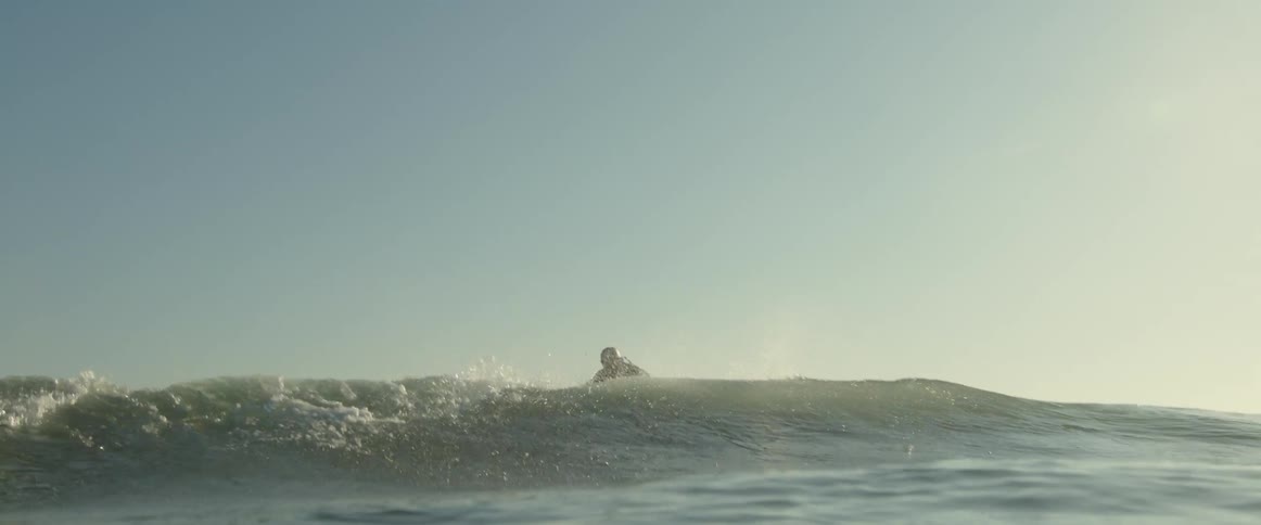 A man surfs while wearing a helmet and jacket