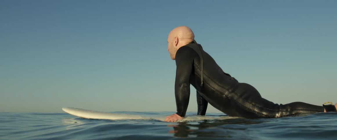 A man is surfing on the ocean water at dusk