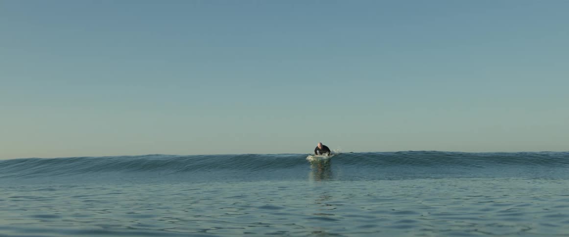 A man sits up on his surfboard letting a wave go