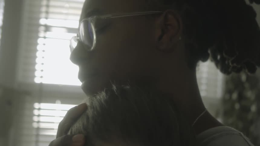 A woman embraces a child while indoors during the day