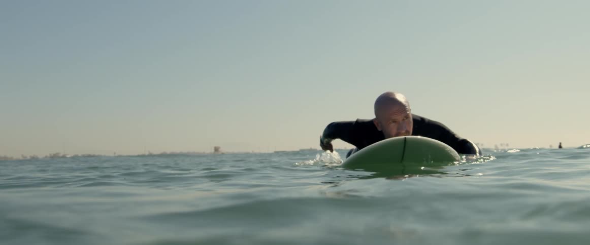 A man is surfing on ocean water during the sun set