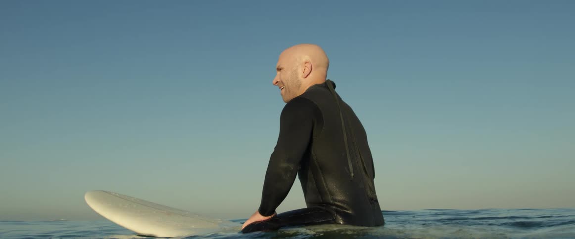 A man is surfing on the ocean water at dusk