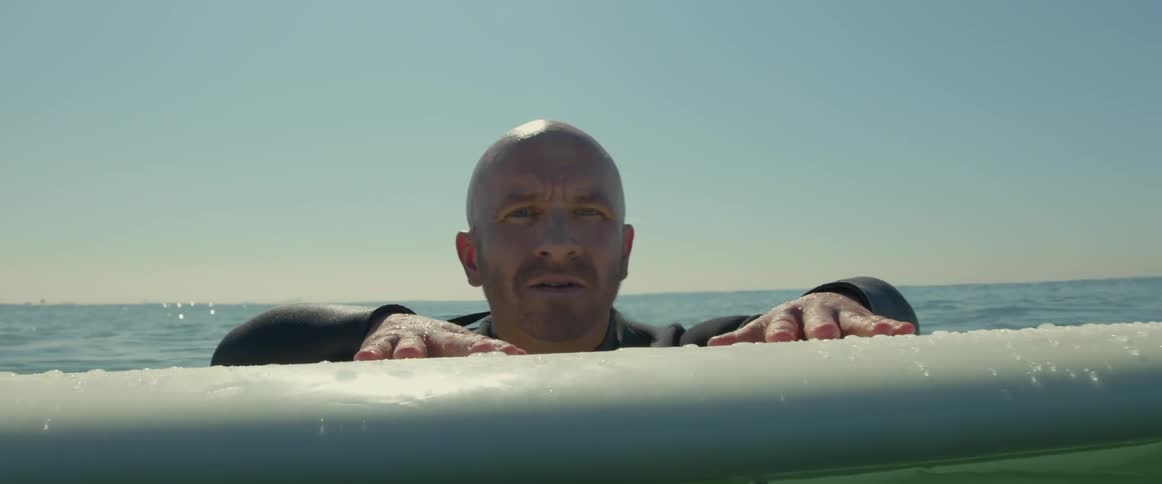 A man is floating in the water holding onto his surfboard
