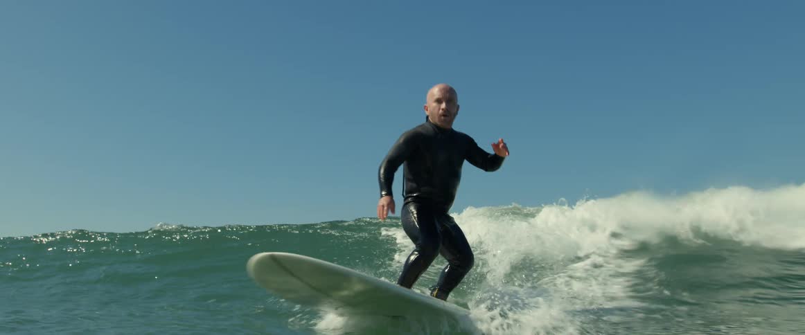 A man is surfing on ocean water during the midday