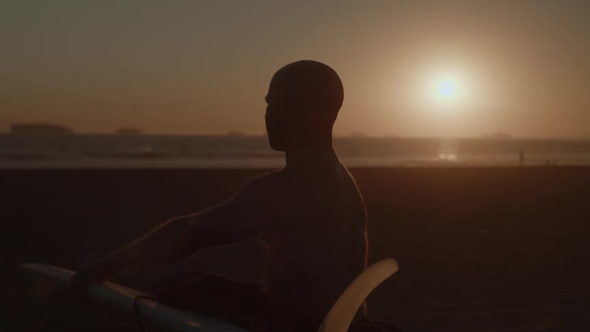 A man is walking at the beach with a surfboard
