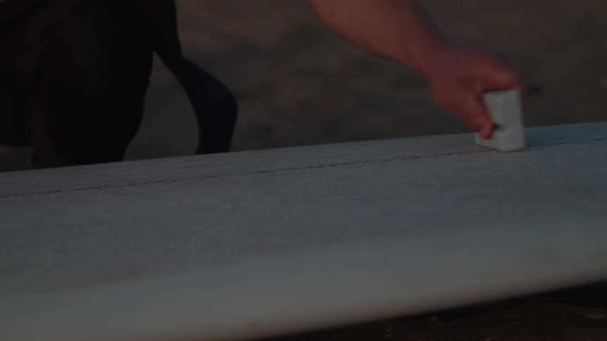 A man waxing a surfboard outdoors