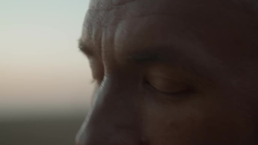 A bald man outside at sunrise