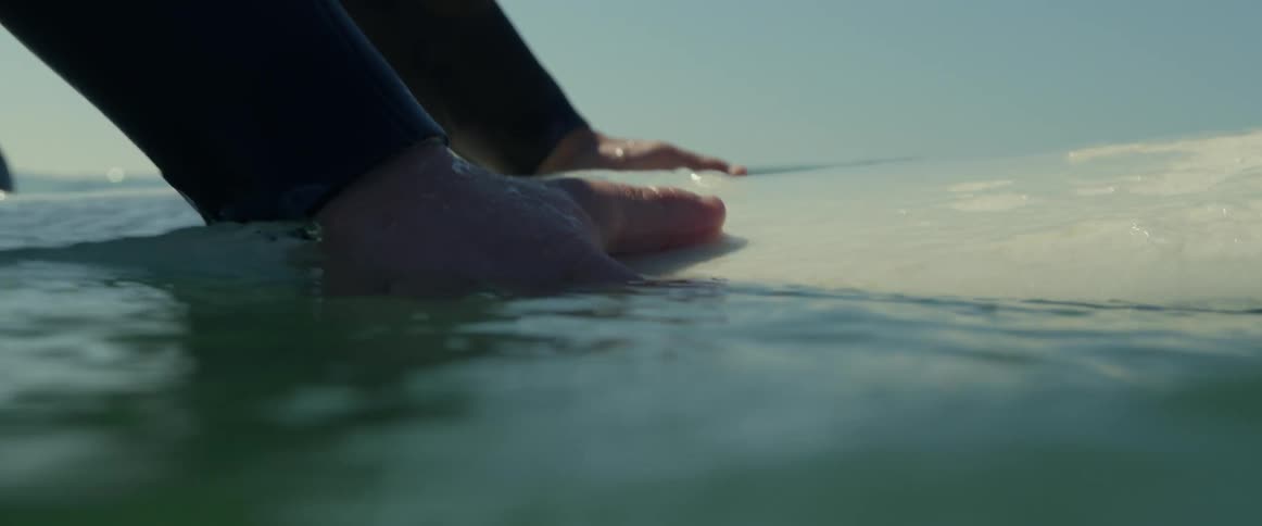 An older white man is on his surfboard in the summer time