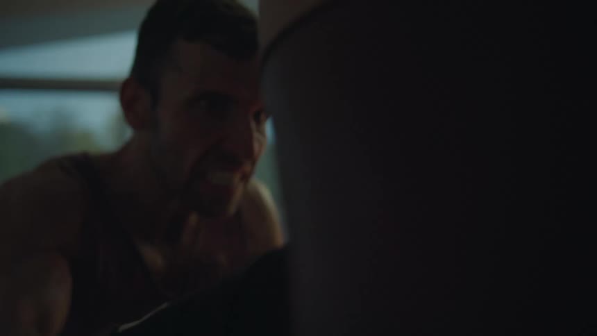 A man throws punches at a boxing bag in his home
