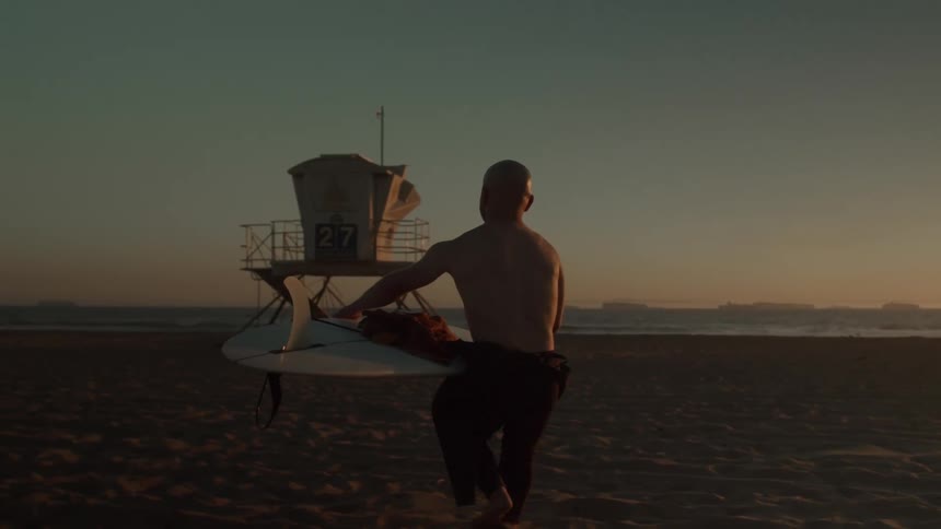 A man carries his surfboard to the water