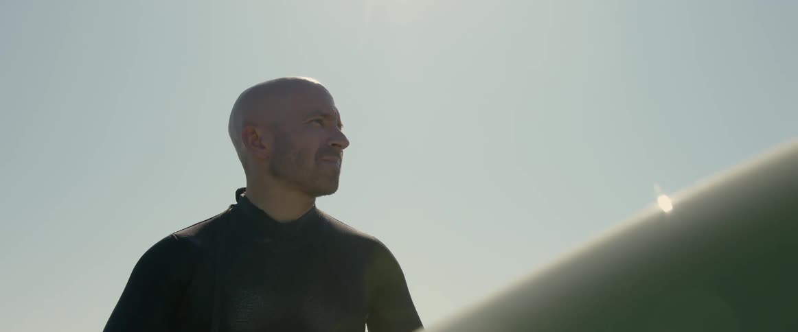 A man is holding his surf board outdoors