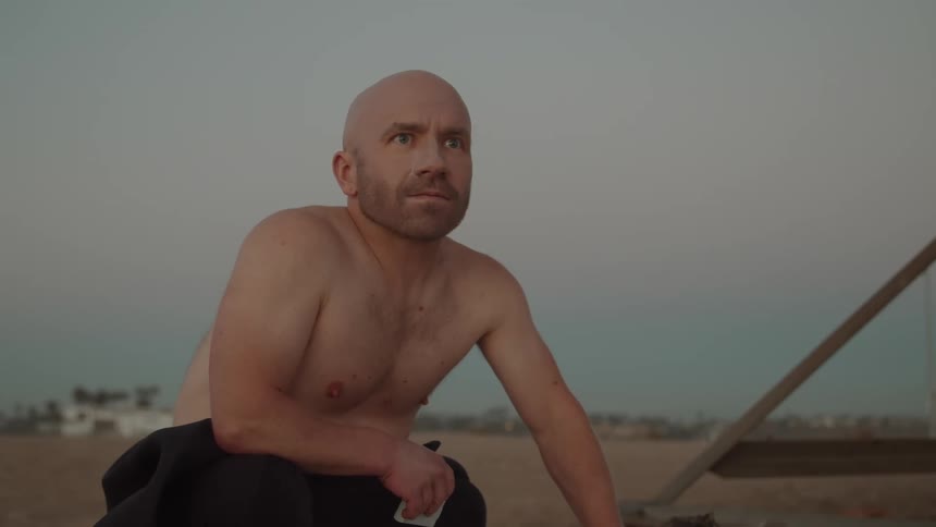 A man smiles as he sits on a beach