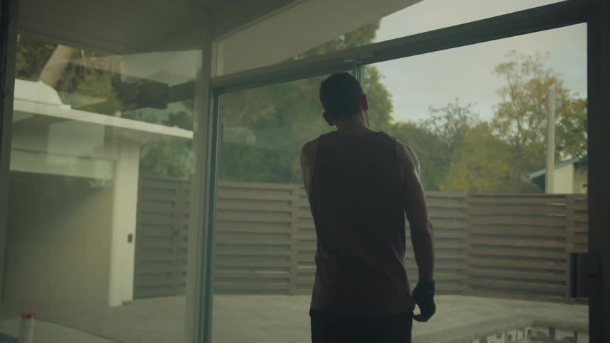 Man walks away from punching bag and toward sliding glass doors
