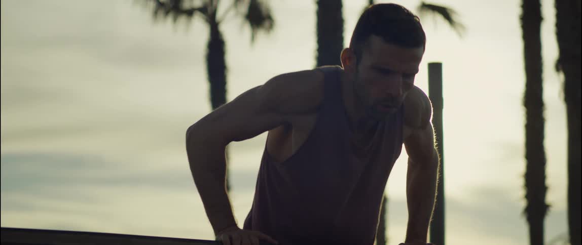 A man does exercises on a wooden handrail outdoors in the evening
