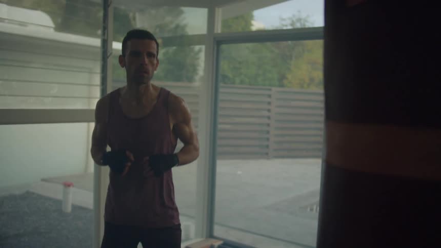 A man at home jumps as he gets ready to throw punches at a punching bag