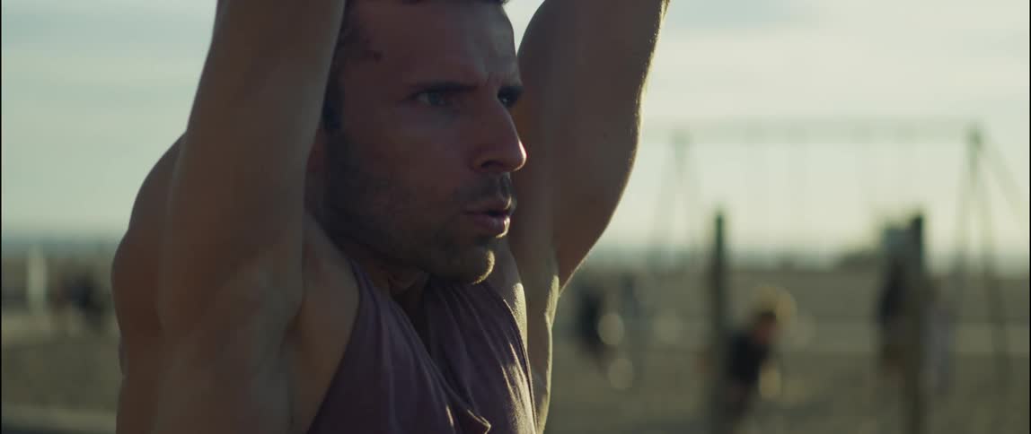 A man swings from playground equipment on a crowded beach