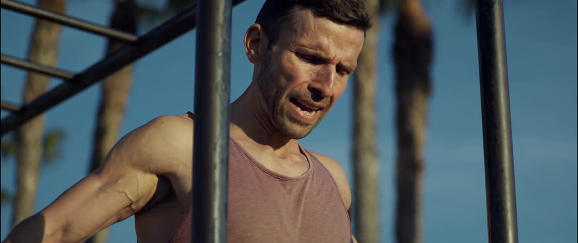 A man in a park stretches his arms across his chest