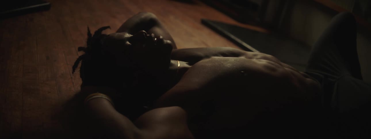 A young black man is laying down on the floor in his home