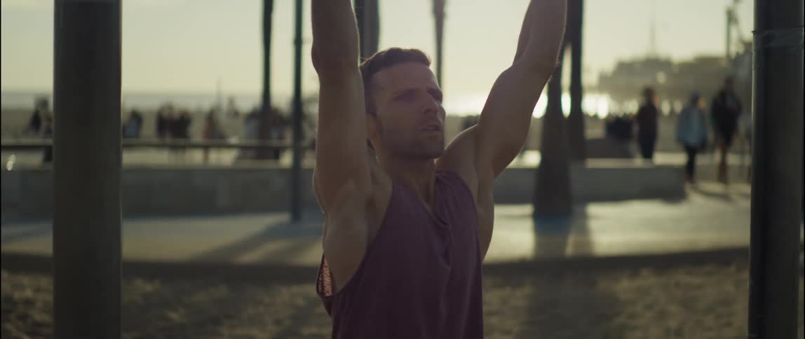 A man exercises on equipment in a public park on a beach during the day