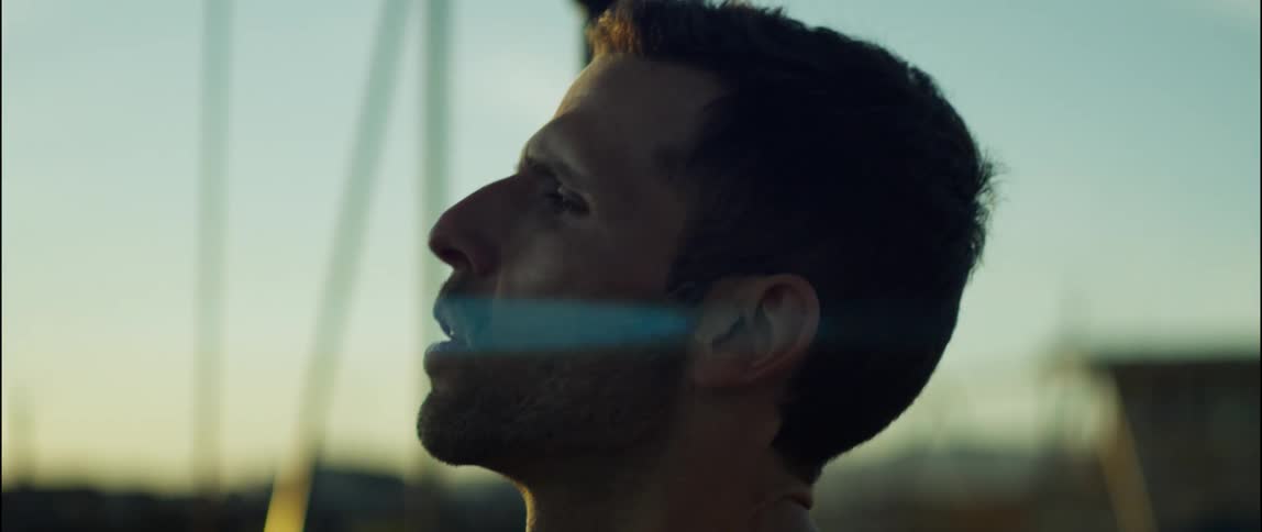 Man stands near swing set at sunset