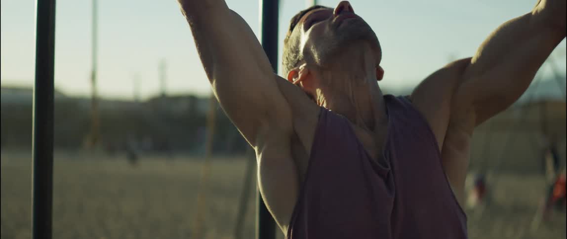 A man is exercising on monkey bars in a park